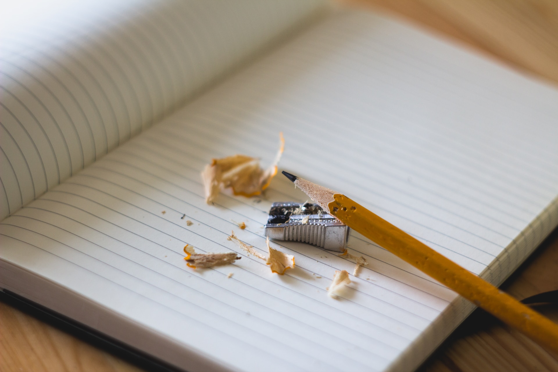 A photo of a blank notebook with a pencil and pencil sharpener.
